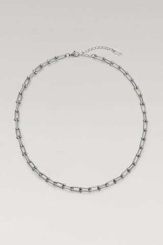 A silver-toned chain link necklace with elongated oval links and a delicate extender chain, displayed on a light gray background.