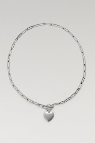 A silver-toned chain necklace with a small heart-shaped pendant, displayed on a clean light gray background.