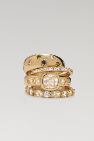 Stack of four gold plated rings: Jude star-set band, a pave band, Mara cushion-cut signet and Aurelia marquise eternity ring