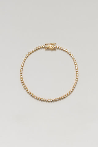 Alma mini tennis bracelet, gold plated, lying in a circle with its box clasp and bezel-set cubic zirconia