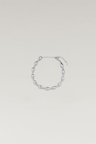 Riva bracelet, silver-tone, lying in a circle with its extender chain and tag, hollow teardrop links