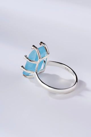 Silver ring with a blue gemstone on a light gray background