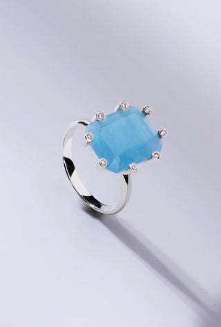 Silver ring with a blue gemstone on a light gray background