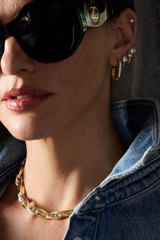 Model in sunglasses wearing a Sabine earring, pear-shaped stone studs and the two-tone Allegra necklace over a denim shirt