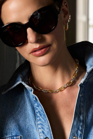 Model in tortoiseshell sunglasses and a denim shirt wearing the two-tone Allegra necklace and U-shaped earrings