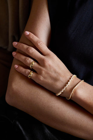 Gold plated Jude rings with a Ramona tennis bracelet and a slim tennis bracelet, worn on crossed hands