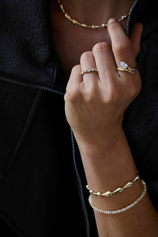 Model in a leather jacket wearing the gold plated Riva necklace and Riva bracelet with a tennis bracelet and stacked rings