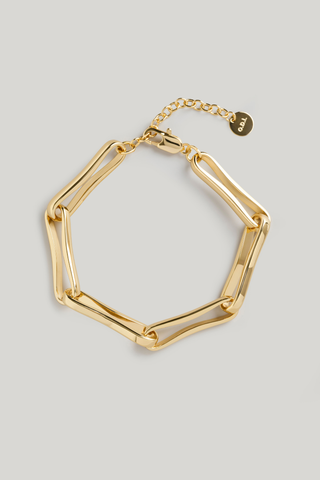 A gold-toned geometric link bracelet with a hexagonal chain-link design and an adjustable chain clasp featuring a small round tag, shown on a neutral light gray background.