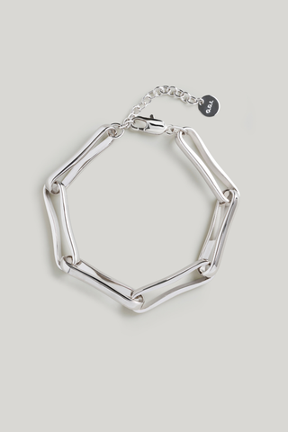 A silver-toned geometric link bracelet with a hexagonal design, shown on a light gray background. It features a lobster clasp, an extender chain, and a small round brand tag with the text 'G&G'.