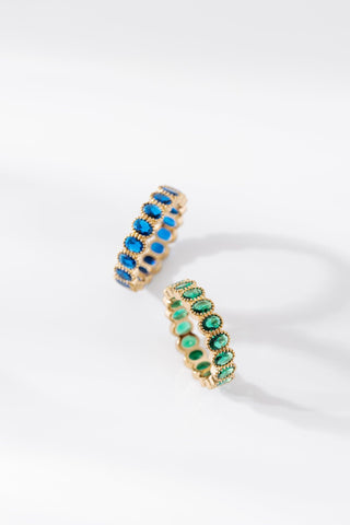 Aurora gold rings shown with blue and green oval gemstones on white background