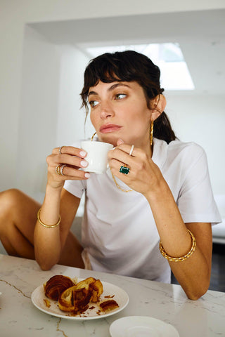 Model wearing Carmela gold bangle paired with hoop earrings and gold necklace