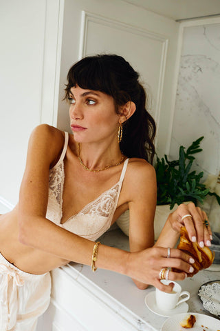 Carmela gold hoop earrings styled with layered gold jewelry and rings