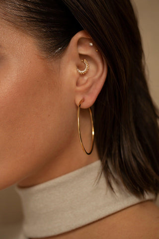Estelle gold hoop earrings worn on the ear with a classic silhouette