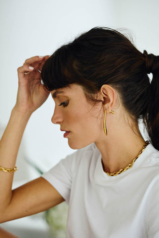 Side profile of model wearing Zara gold chain necklace and gold earrings
